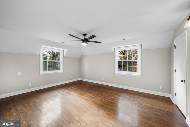 empty room with vaulted ceiling, a wealth of natural light, dark wood-type flooring, and ceiling fan