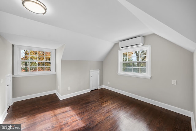 bonus room featuring a wall mounted air conditioner, dark hardwood / wood-style floors, vaulted ceiling, and a healthy amount of sunlight