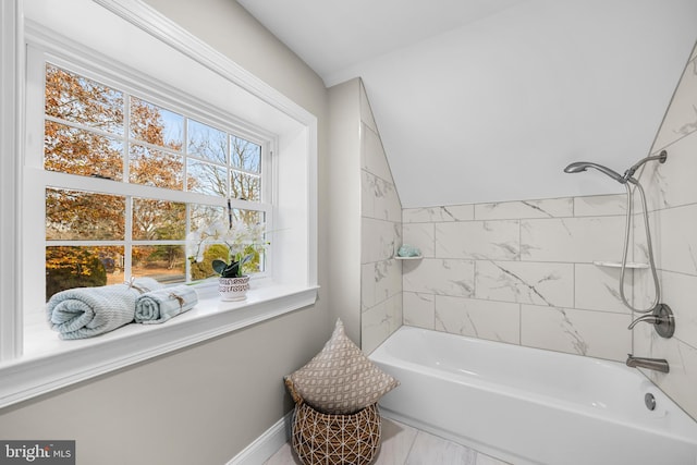 bathroom with vaulted ceiling and tiled shower / bath