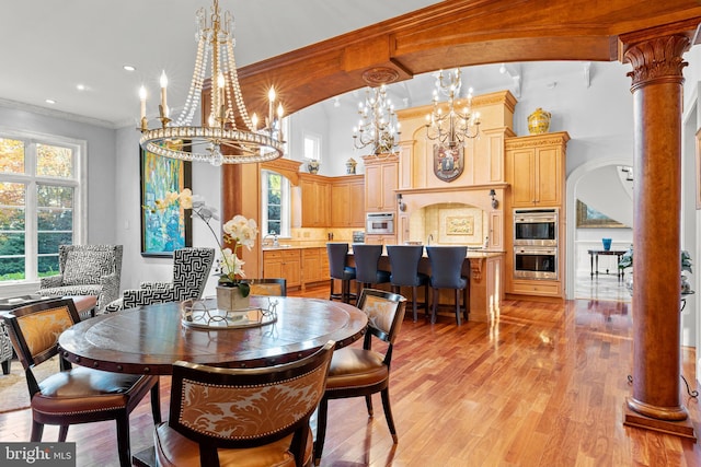 dining space with decorative columns, light hardwood / wood-style floors, a high ceiling, and ornamental molding