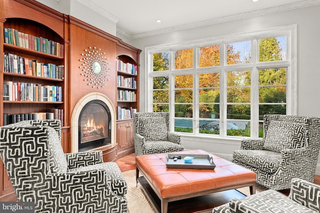 living area featuring built in shelves and crown molding