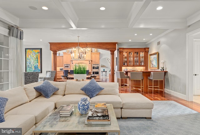 living room with ornate columns, crown molding, beamed ceiling, and a chandelier