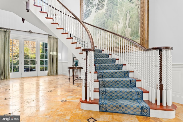 stairway featuring french doors and a high ceiling