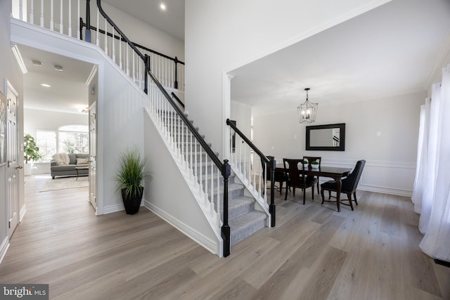 stairs with an inviting chandelier, baseboards, and wood finished floors