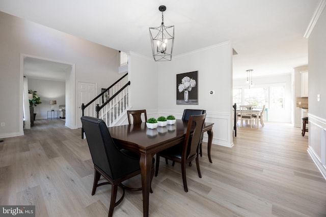 dining room featuring light wood-style floors, crown molding, a chandelier, and stairway