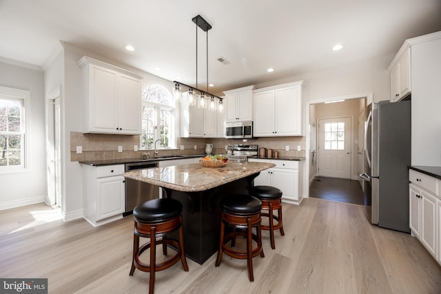 kitchen featuring a center island, light wood finished floors, appliances with stainless steel finishes, and white cabinetry