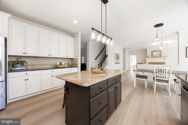 kitchen featuring white cabinets, tasteful backsplash, a kitchen island, and light wood-type flooring