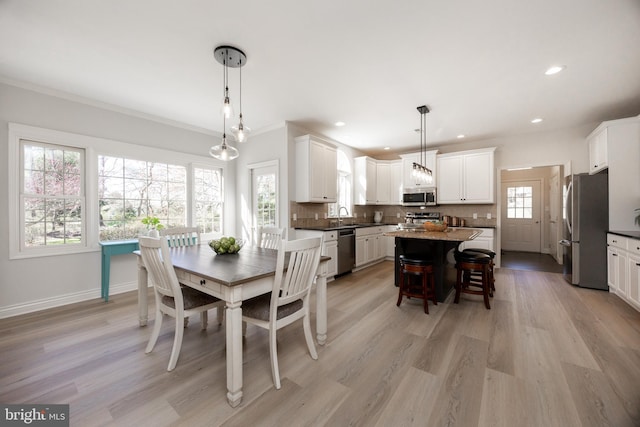 dining area featuring recessed lighting, baseboards, crown molding, and light wood finished floors