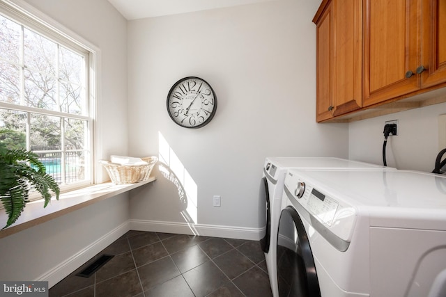 laundry area featuring dark tile patterned flooring, baseboards, washing machine and dryer, and cabinet space