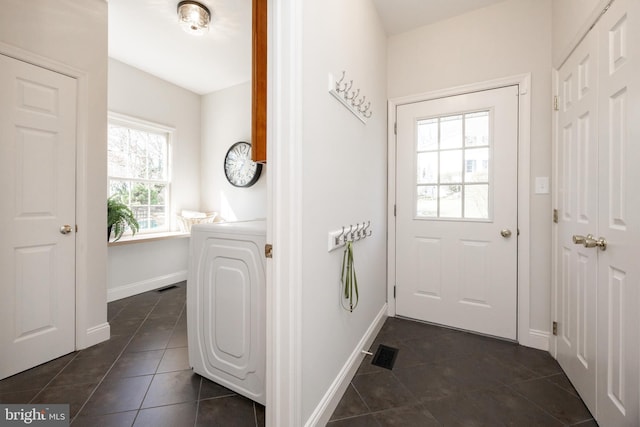 entryway with washer / dryer, dark tile patterned floors, baseboards, and visible vents