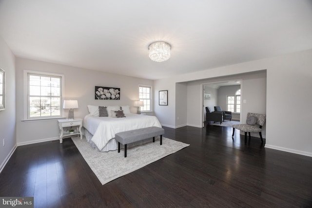 bedroom with an inviting chandelier, baseboards, dark wood-style floors, and multiple windows