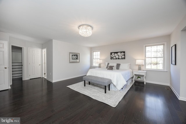 bedroom with dark wood-style flooring, baseboards, and a notable chandelier