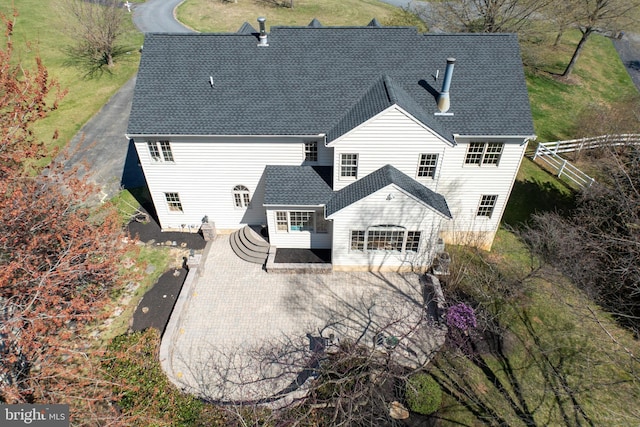 back of house featuring a patio and roof with shingles