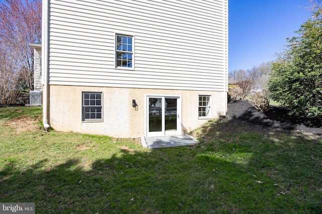 back of property featuring a lawn and stucco siding