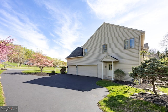 traditional-style house featuring an attached garage and aphalt driveway