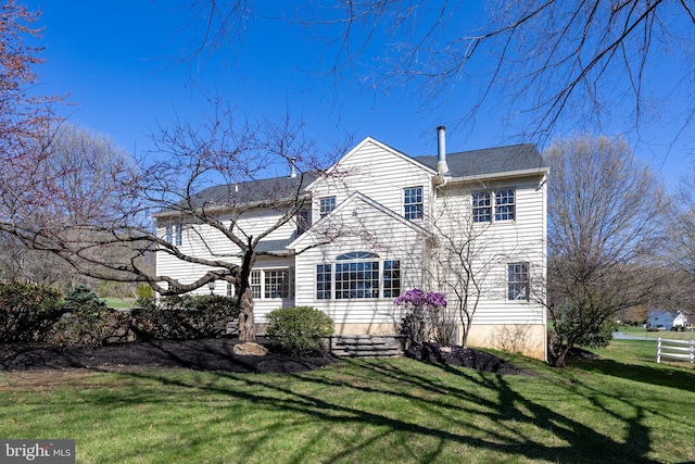 back of house featuring a lawn and fence