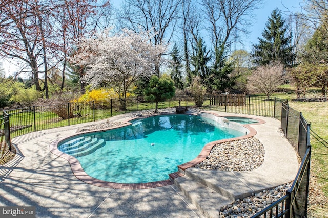 view of pool with a patio area, fence, and a pool with connected hot tub