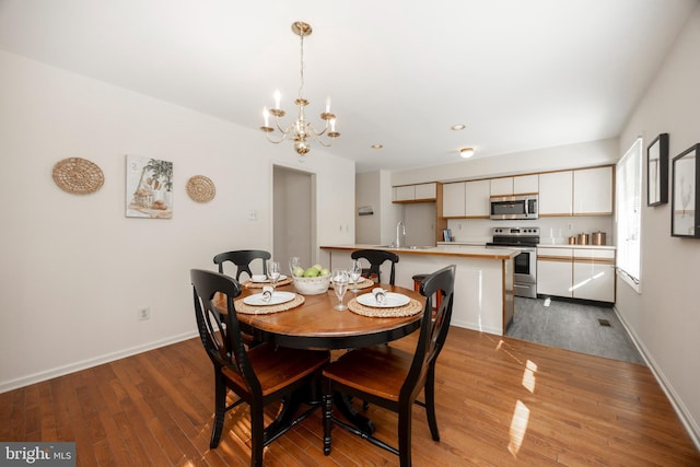 dining area with sink, a chandelier, and light hardwood / wood-style flooring