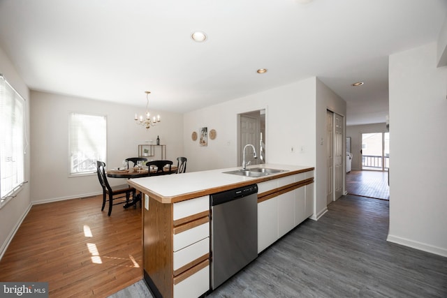 kitchen with dark wood-type flooring, sink, hanging light fixtures, stainless steel dishwasher, and white cabinets