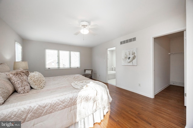 bedroom with connected bathroom, a walk in closet, dark hardwood / wood-style flooring, a closet, and ceiling fan