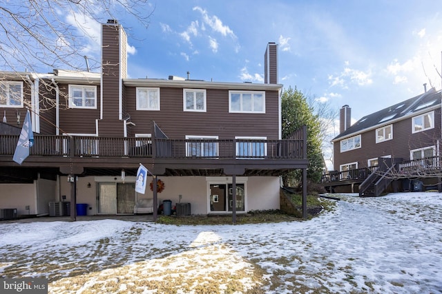 snow covered property with a wooden deck and central air condition unit