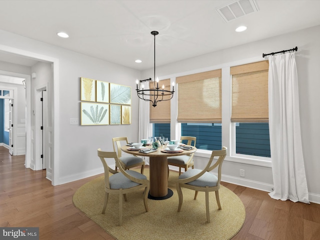 dining area with hardwood / wood-style floors and a notable chandelier