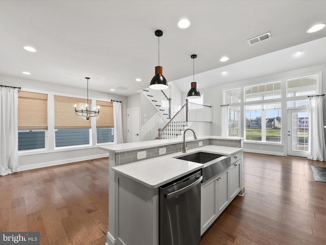 kitchen featuring sink, stainless steel dishwasher, dark hardwood / wood-style floors, pendant lighting, and a center island with sink