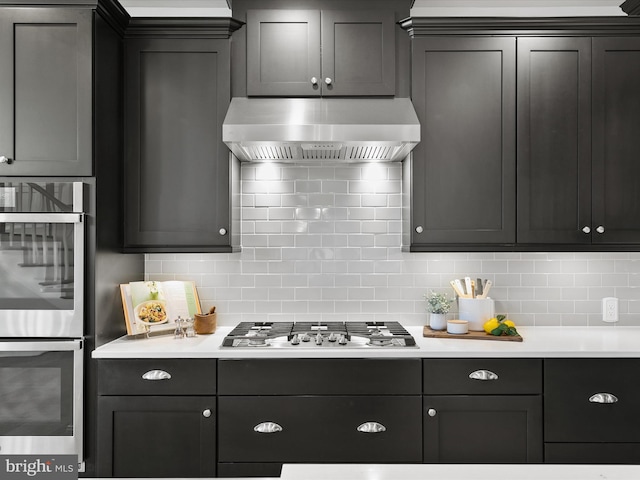 kitchen with wall chimney exhaust hood, backsplash, and appliances with stainless steel finishes