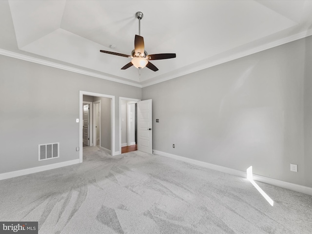 carpeted spare room with a tray ceiling, ceiling fan, and ornamental molding