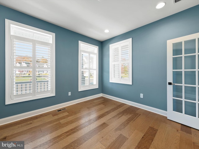 spare room with plenty of natural light and hardwood / wood-style floors