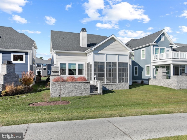 rear view of property featuring a yard and a sunroom