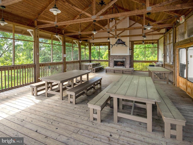 unfurnished sunroom featuring wooden ceiling, lofted ceiling with beams, and an outdoor stone fireplace