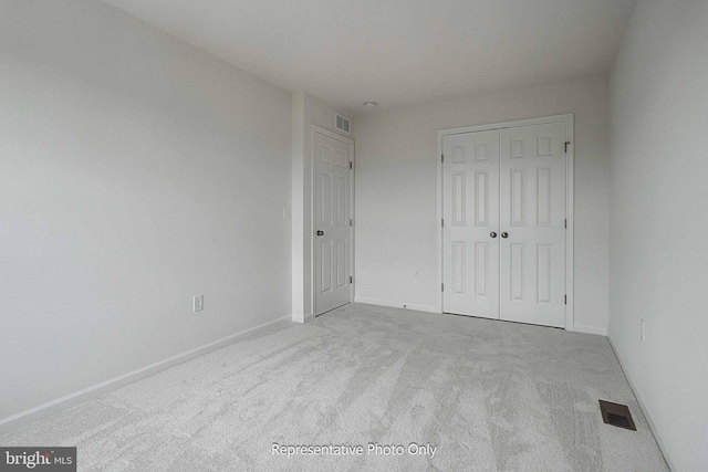 unfurnished bedroom featuring light colored carpet and a closet