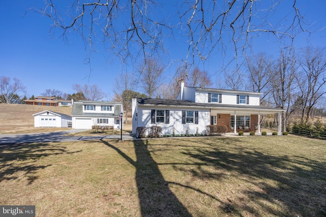 view of front of property featuring a porch, a garage, a front yard, and a chimney