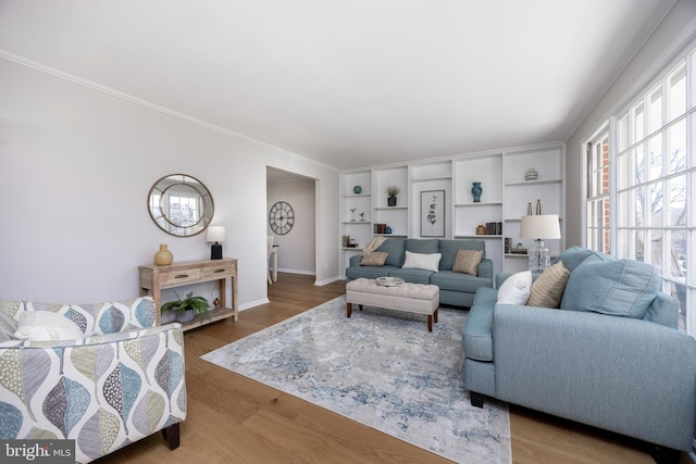 living area featuring baseboards, wood finished floors, and ornamental molding