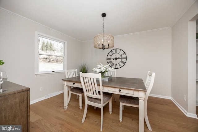 dining space with ornamental molding, baseboards, and wood finished floors