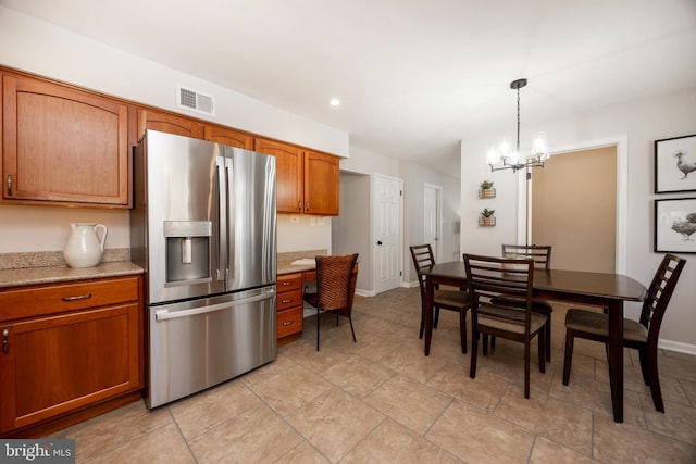 kitchen featuring visible vents, baseboards, stainless steel fridge with ice dispenser, decorative light fixtures, and brown cabinetry