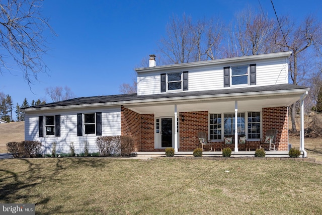 traditional-style house with a chimney, brick siding, a porch, and a front yard