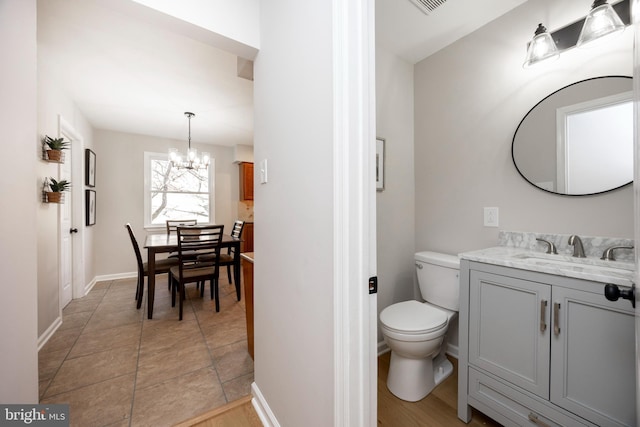 bathroom with visible vents, a notable chandelier, toilet, baseboards, and vanity