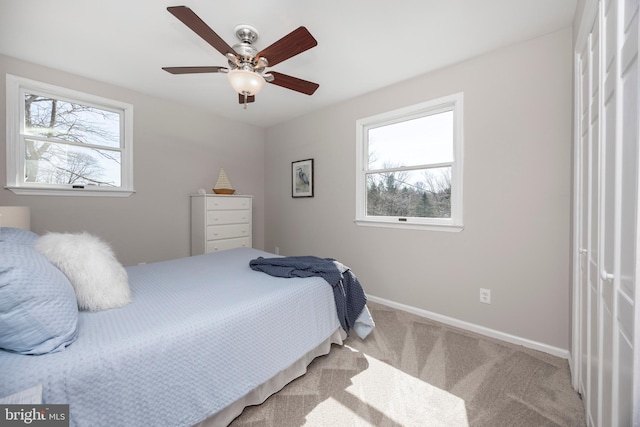 carpeted bedroom with baseboards, multiple windows, and ceiling fan