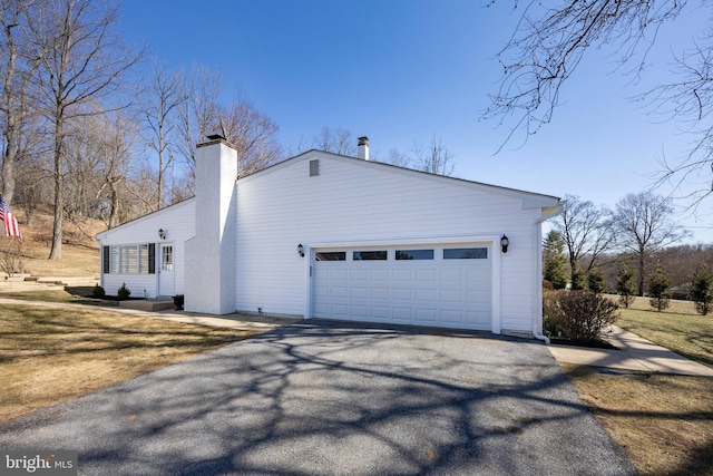 view of home's exterior with a garage, driveway, and a chimney