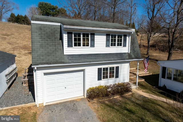 colonial inspired home featuring driveway, a garage, and roof with shingles