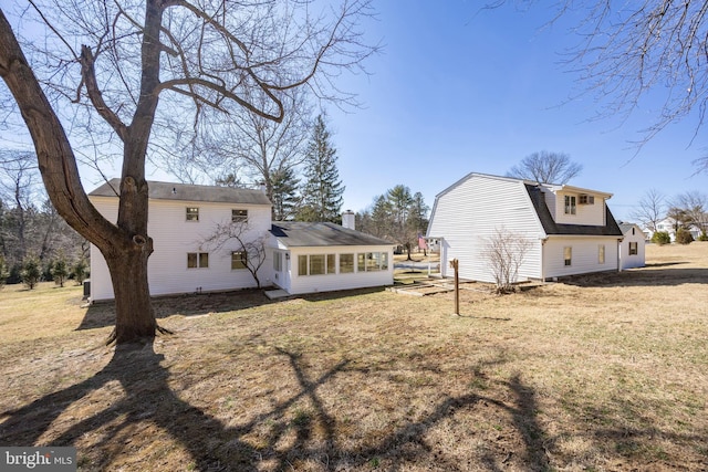 back of house with a gambrel roof, a lawn, and a sunroom