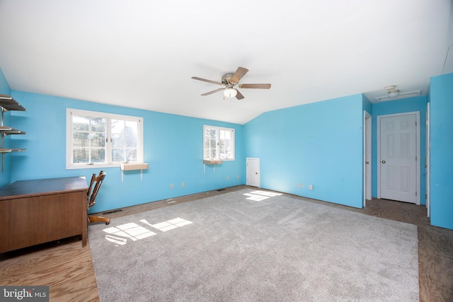 unfurnished office featuring visible vents, a ceiling fan, lofted ceiling, and carpet floors