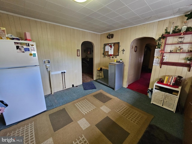 kitchen with dark colored carpet, white fridge, and wooden walls