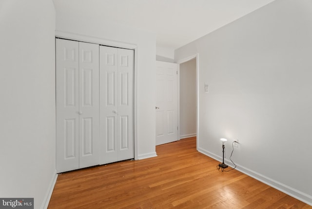 unfurnished bedroom with light wood-type flooring and a closet