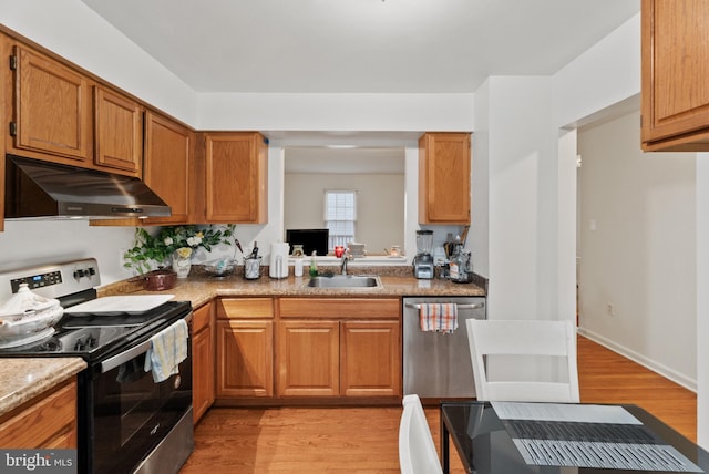 kitchen with light stone countertops, sink, light wood-type flooring, and stainless steel appliances