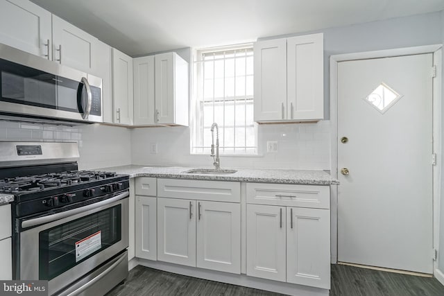 kitchen featuring sink, light stone countertops, dark hardwood / wood-style flooring, white cabinetry, and stainless steel appliances