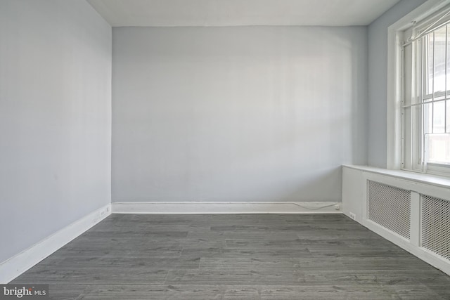 unfurnished room featuring radiator heating unit and dark wood-type flooring