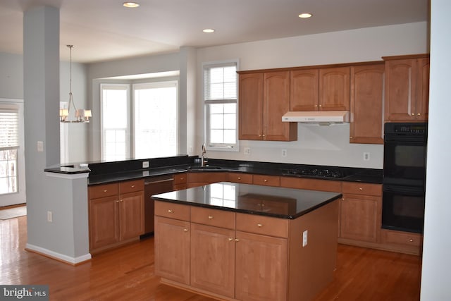 kitchen with hanging light fixtures, light hardwood / wood-style flooring, a wealth of natural light, and black appliances